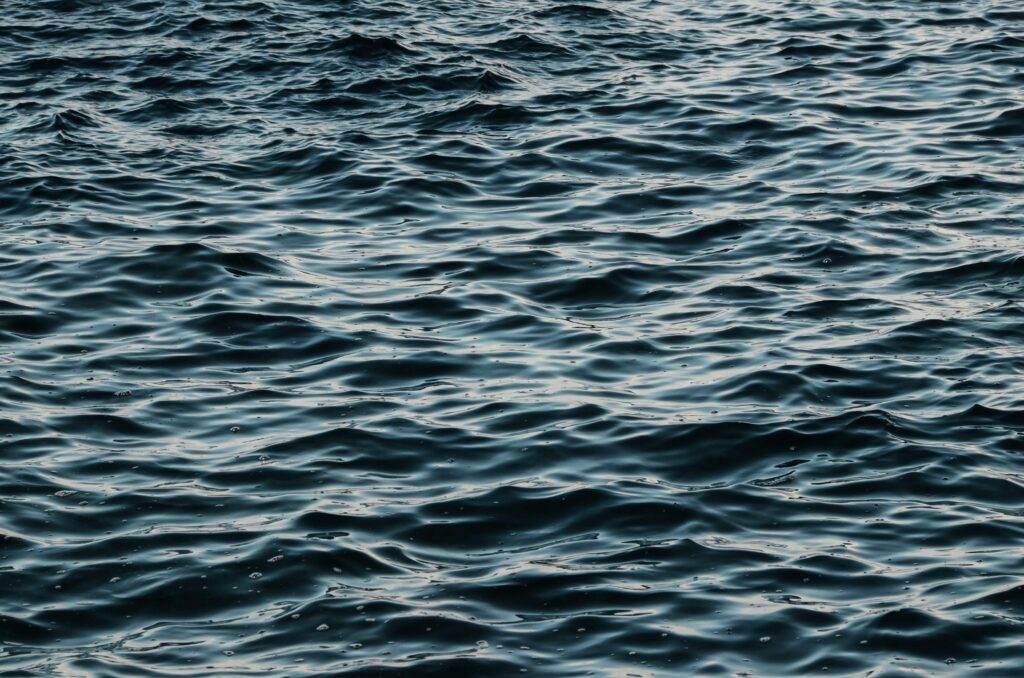 Donkerblauw zeewater met kleine ritmische golven en zachte witte reflecties op het oppervlak.